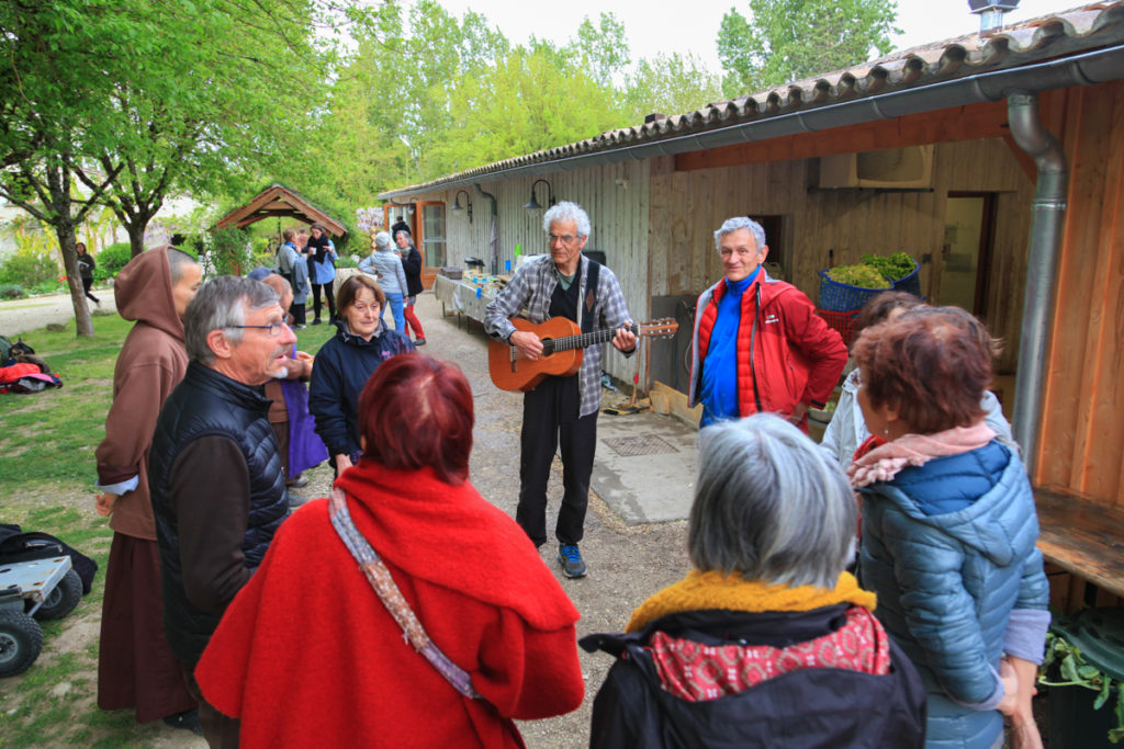 Un groupe réuni en cercle chante. Un des ses membres joue de la guitare